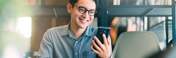 Man smiling as he holds and looks at an Android device
